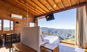 A wooden cabin with a bed, a table, and a TV.