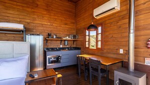 Una cocina compacta con refrigerador, estufa, horno y una pequeña mesa de comedor con sillas.