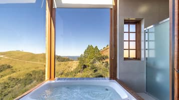 Un jacuzzi en un balcón con vistas a un paisaje montañoso.
