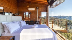 A wooden cabin bedroom with a bed, bedside table, and a TV mounted on the wall. - Cabana espetacular região serrana VST008 (Anitápolis)
