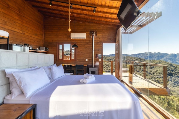 A wooden cabin bedroom with a bed, bedside table, and a TV mounted on the wall.