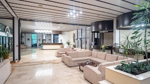 A modern lobby with a reception desk, beige sofas, a coffee table, and potted plants. - Hotel Issa - Double Room Sea View 40 (Vis)