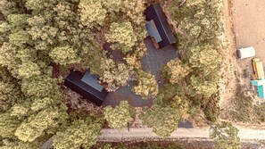 An aerial view of a property with two buildings surrounded by dense trees.