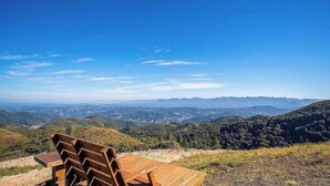 A wooden bench overlooking a mountainous landscape with clear skies. - Chalé c\Jacuzzi prox. de Florianópolis VST024 (Anitapolis)