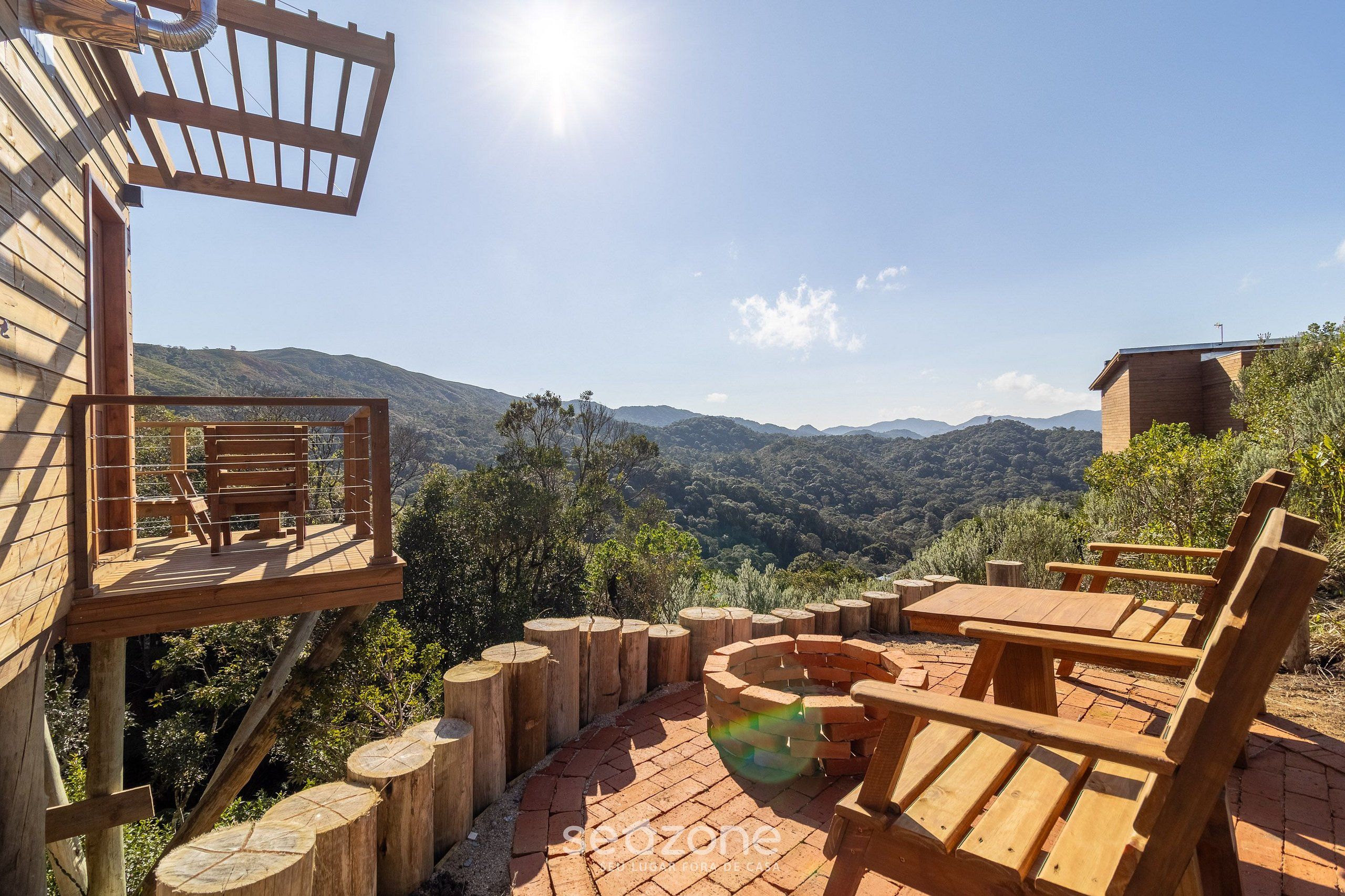 Une terrasse en bois avec une table et des chaises, offrant une vue sur un paysage montagneux.