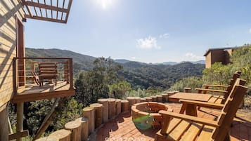 Une terrasse en bois avec une table et des chaises, offrant une vue sur un paysage montagneux.