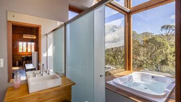 Un baño moderno con un ventanal amplio, un tocador de madera, una bañera y una zona de ducha.