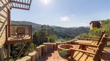 Une terrasse en bois avec une table et des chaises, offrant une vue sur un paysage montagneux.