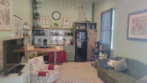 A cozy living room with a sofa, a TV, and a kitchen area with a microwave, refrigerator, and various kitchen items. - Romantic Barn I Chickens, Porch, Near City,
Dog Friendly (Hollywood)