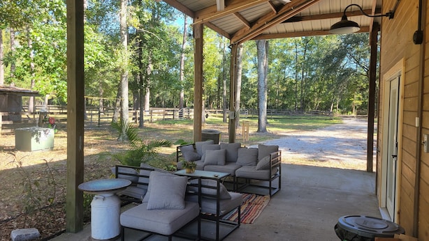 A covered outdoor seating area with a table and chairs, surrounded by trees and a gravel path. - Romantic Barn I Chickens, Porch, Near City,
Dog Friendly (Hollywood)