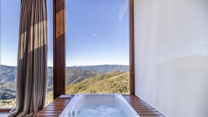 Una habitación con piso de madera, una bañera blanca y vistas a un paisaje montañoso.