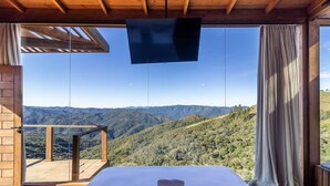 Una habitación con una cama, televisión y vistas a un paisaje montañoso.