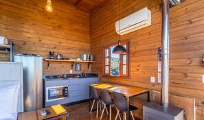 A compact kitchen with a refrigerator, stove, microwave, and a small dining area with chairs and a table.