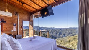 Un dormitorio con un amplio ventanal que da a un paisaje montañoso.