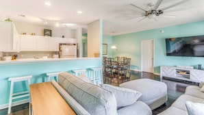 A modern living room with a sofa, ottoman, and a dining area with chairs and a table. - 1 Mi to Beach, Near Golf! North Myrtle Beach Condo (North Myrtle Beach)
