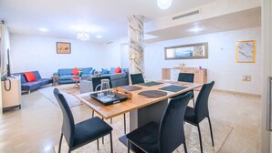 A modern living room with a sofa, coffee table, and dining table with chairs. - Agadir Bay Beautiful apartment overlooking the pool and nearby beach. (Agadir)