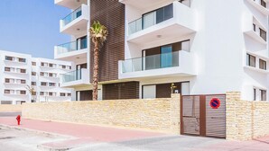 A modern multi-story building with balconies, a stone wall, and a red fire hydrant. - Agadir Bay Beautiful apartment overlooking the pool and nearby beach. (Agadir)