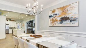 A modern dining area with a long table and chairs, a chandelier, and a large abstract painting on the wall. - West ATL Home w/ Great Outdoor Space: 4 Mi to Dtwn (Atlanta)