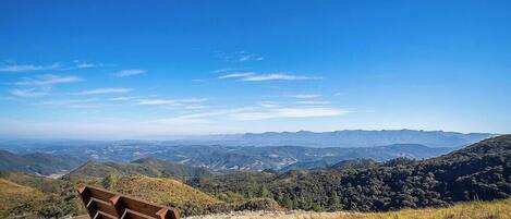 A wooden bench overlooking a mountainous landscape with clear skies.
