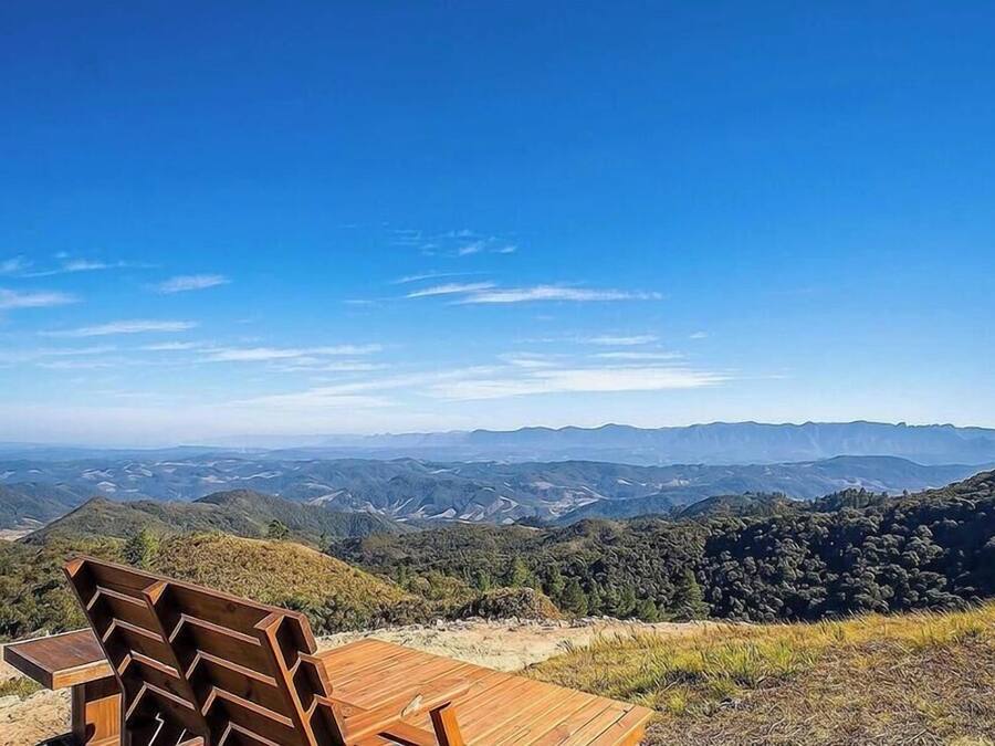 Un banco de madera con vista a un paisaje montañoso y cielos despejados.