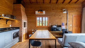 Interior acogedor de una cabaña con detalles de madera, una chimenea de ladrillo, una mesa de comedor y un televisor.
