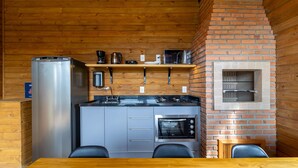 A compact kitchen with a refrigerator, coffee maker, kettle, and a built-in oven. - Cabana c/ vista e jacuzzi Serra Catarinense VST025 (Anitápolis)