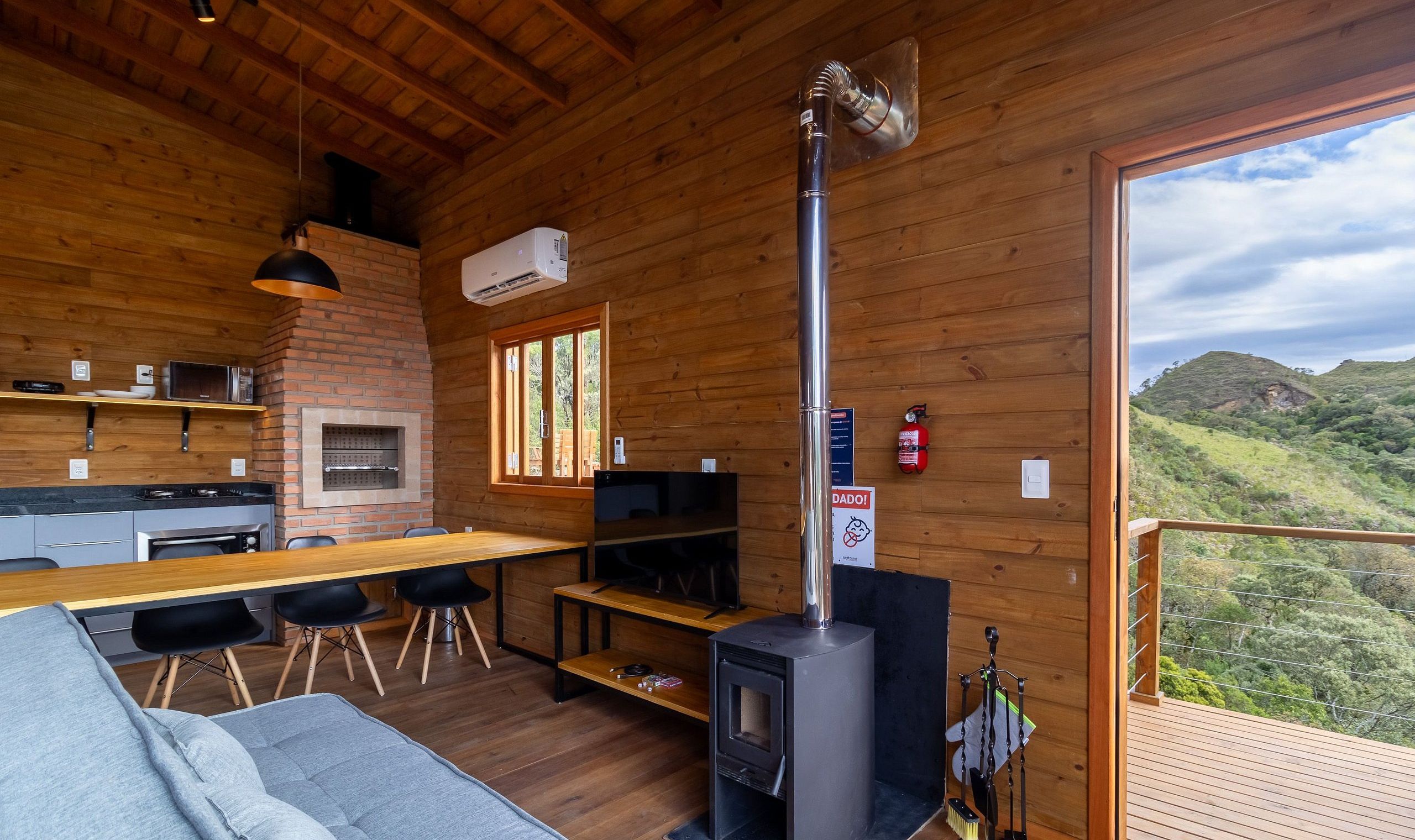 A wooden cabin interior with a kitchen, dining area, and a fireplace.