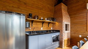 Cocina compacta con refrigerador de acero inoxidable, horno empotrado, cafetera y horno de ladrillo.