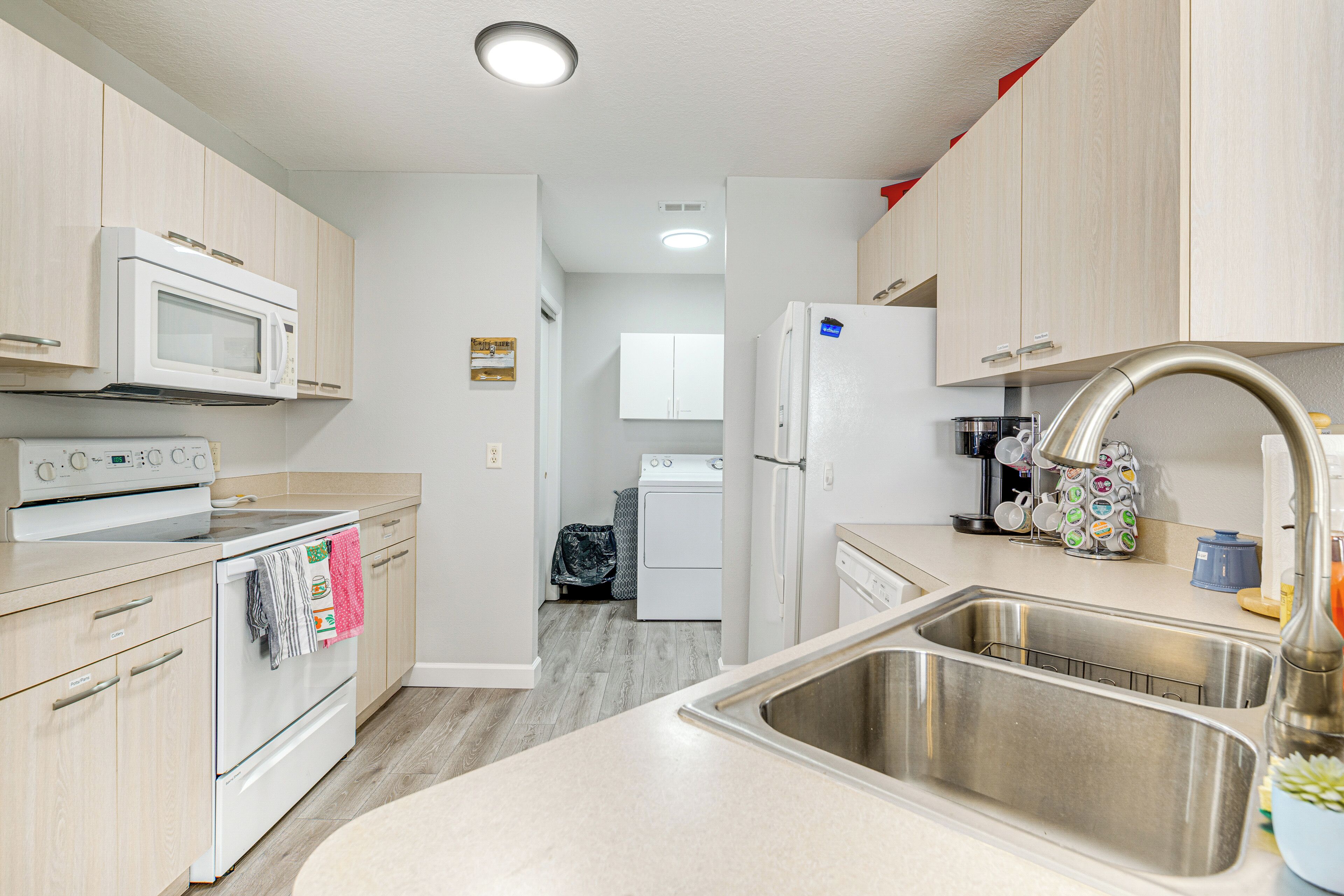 A modern kitchen with stainless steel appliances, a double sink, and light wood cabinetry.