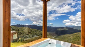 A wooden deck with a hot tub overlooking a mountainous landscape. - Cabana incrível com vista VST010 (Anitápolis)