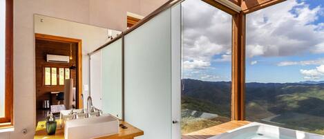 A modern bathroom with a large window offering a scenic view of a mountainous landscape.