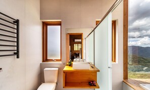 A modern bathroom with a toilet, sink, and a window offering a view of the outdoors. - Cabana incrível com vista VST010 (Anitápolis)
