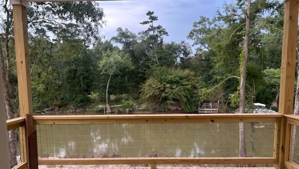 Terraza de madera con vistas a un área boscosa y un cuerpo de agua.