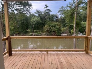 Una terrassa de fusta amb vista a una zona boscosa i un cos d'aigua.