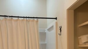 Un baño con inodoro, ducha y barra para toallas.