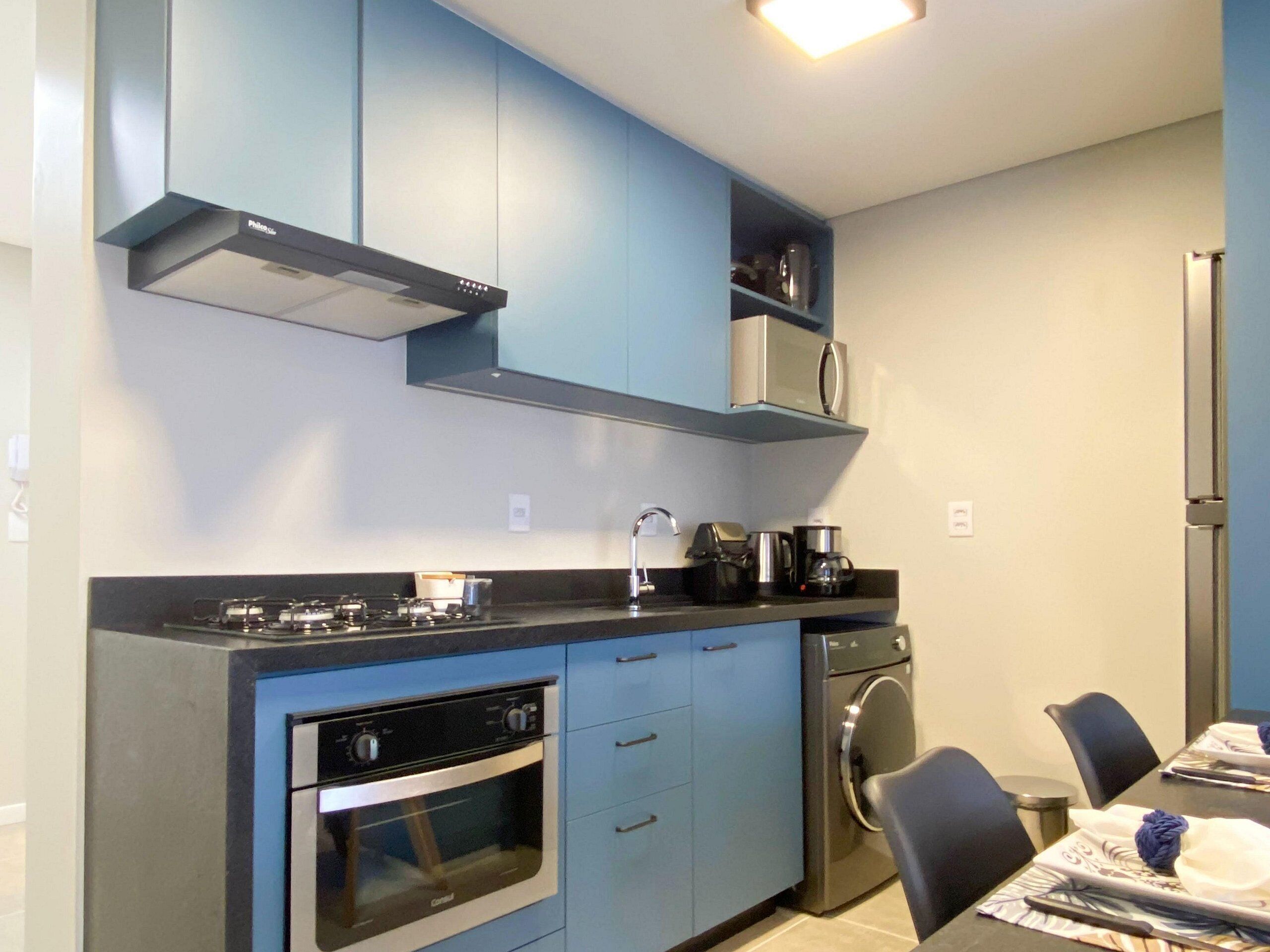 A compact kitchen with a gas stove, oven, microwave, and a washing machine.