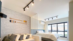 Un dormitorio moderno con sofá, cama y un amplio ventanal.