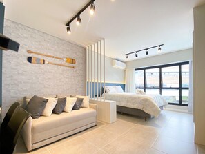 A modern bedroom with a sofa, a bed, and a large window.