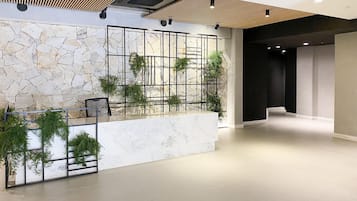 A modern lobby with a stone wall, a reception desk, and a staircase.