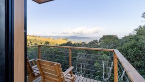 Une terrasse en bois offrant une vue sur un paysage vallonné et un bâtiment situé au loin.