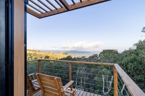 Una terraza de madera con vistas a un paisaje montañoso y un edificio lejano.
