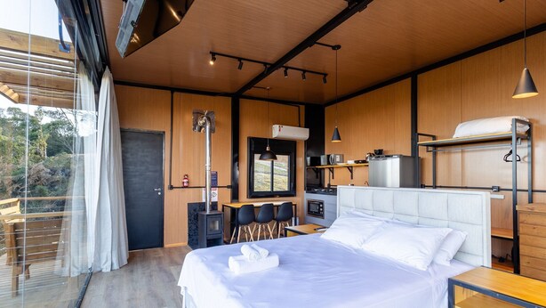 Une chambre d’hôtel moderne dotée d’un grand lit, d’un bureau, d’une kitchenette et offrant une vue sur l’extérieur.