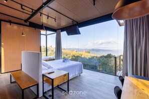 Un dormitorio moderno con un ventanal grande, una cama, un escritorio y una silla.