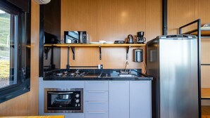A compact kitchen with a built-in oven, a coffee maker, and a refrigerator. - Cabana jacuzzi e vista montanhas VST031 (Anitápolis)