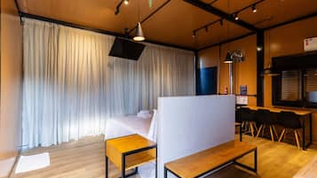 Una habitación de hotel con una cama, un escritorio, un banco y un comedor con sillas.