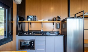 A compact kitchen with a built-in oven, a coffee maker, and a refrigerator.