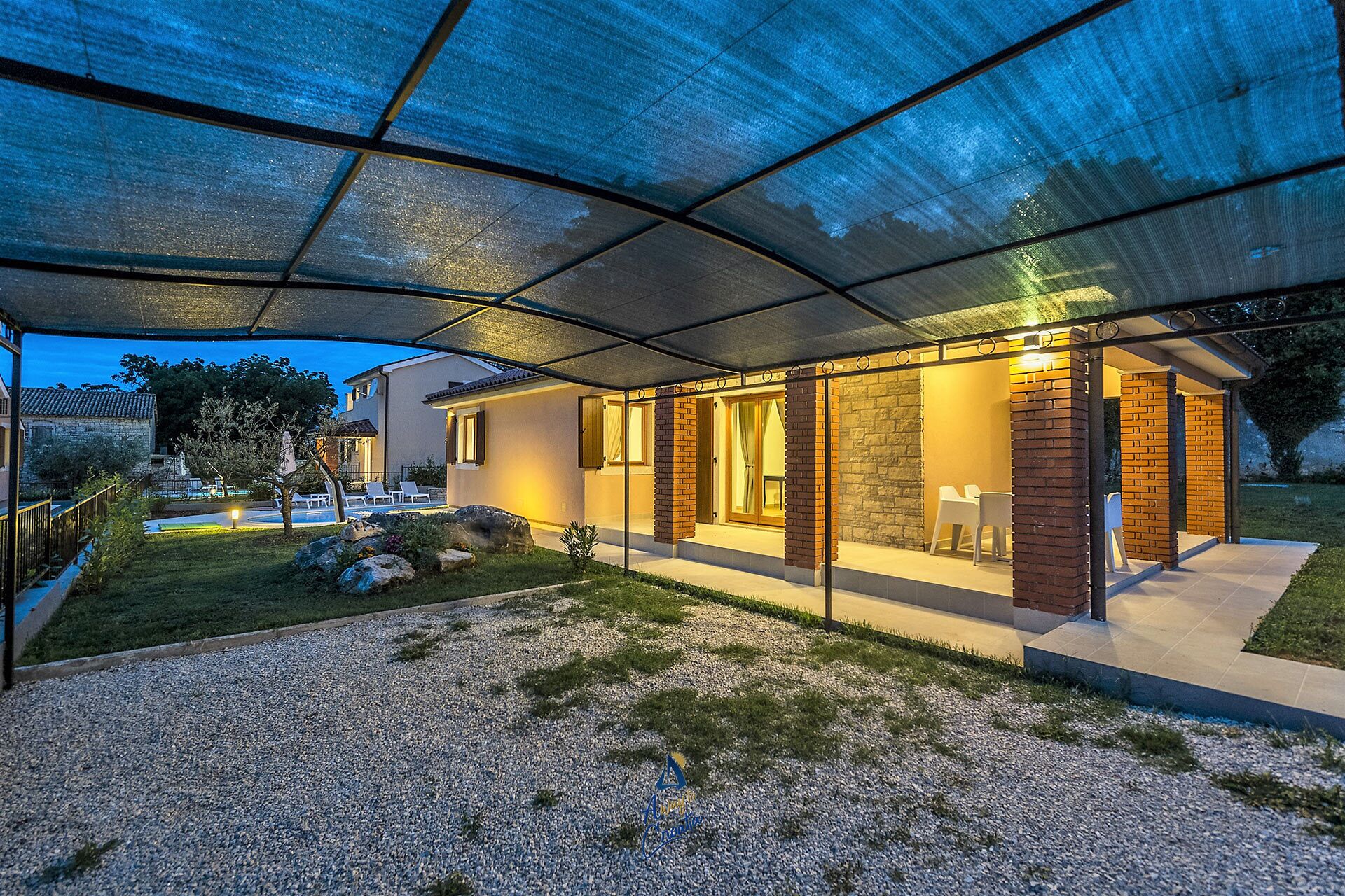 Een modern huis met een overdekt terras, een zwembad en een verzorgde tuin.