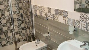 Une salle de bain avec une douche, deux toilettes et deux lavabos.