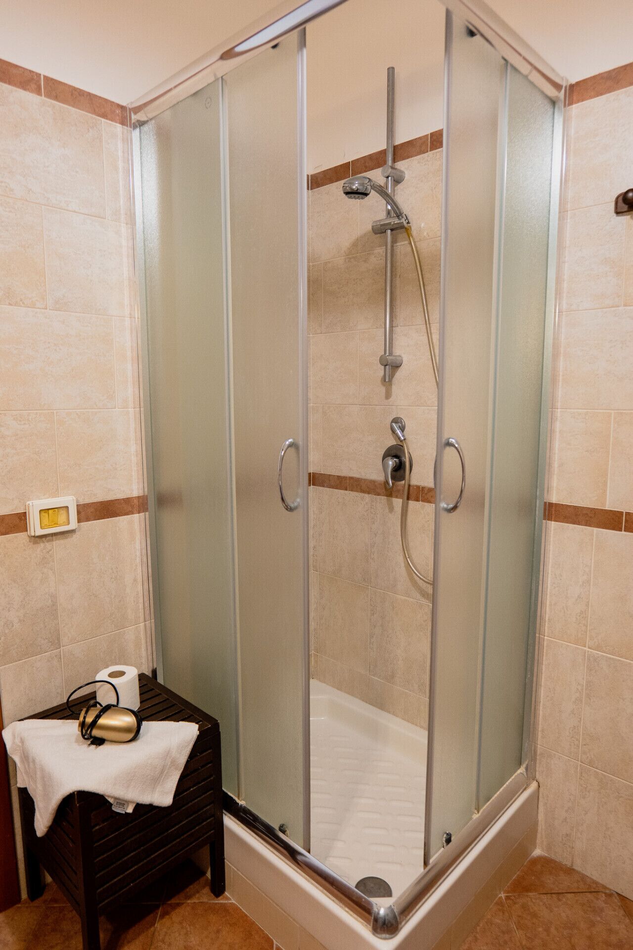 Une douche fermée par des parois en verre, dotée d’un pommeau de douche à main et d’un flexible de douche à main.