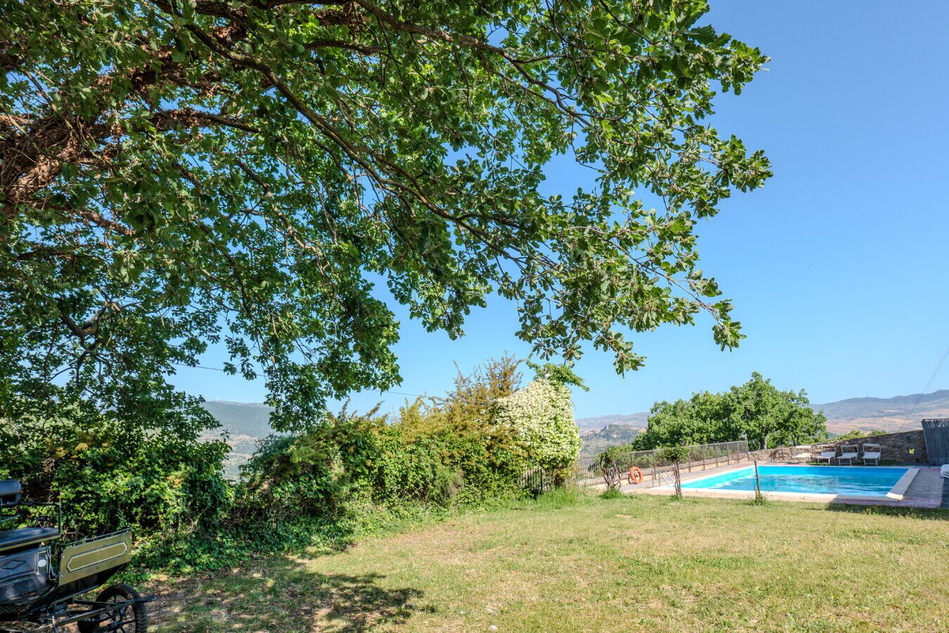 Ein Garten mit Schwimmbad, Rasen und Blick auf ferne Hügel.